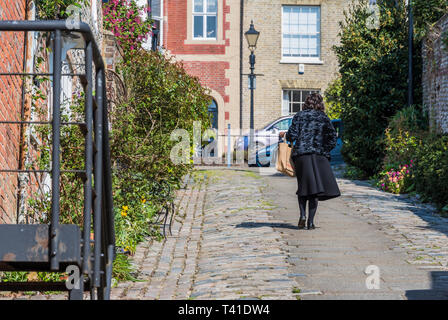 Une femme marchant sur une colline raide à Tarrant Street, une route pavée à Arundel, West Sussex, Angleterre, Royaume-Uni. Banque D'Images