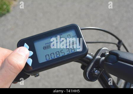 Un homme part appuie sur un bouton d'un scooter électronique noir location. Ordinateur de vélo installé sur un guidon de vélo. L'homme en appuyant sur un bouton sur l'e-bike Banque D'Images