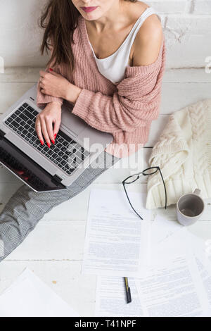 Jeune femme assise sur le sol dans un appartement scandinave intérieur avec un ordinateur portable, d'étudier le droit, offres de fille au travail, l'apprentissage à distance, l'élève onl Banque D'Images