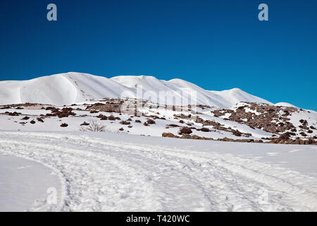 La route de Nida Plateau recouvert de neige. Dans l'arrière-plan les plus hauts sommets du Mont Psiloritis. Rethymnon, Crète, Grèce. Banque D'Images