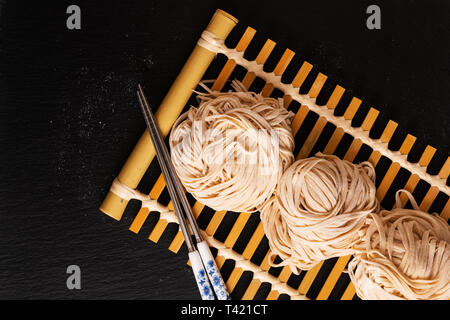 Concept alimentaire asiatique oriental fait maison uncook nouilles aux œufs sur le plateau en bambou avec copie espace Banque D'Images