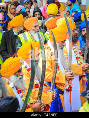 Gravesend, Kent, Royaume-Uni, 13 avril 2019. Les cinq Sikh hommes qui représentent le Panj Pyare (cinq bien-aimés), à l'avant de la procession, suivis du flotteur contenant le sanctuaire. Les participants sikhs portent le kirpan traditionnel, un poignard ou une épée, et le turban. Des milliers de spectateurs et de visiteurs religieux bordent les rues de Gravesend dans le Kent pour observer et participer à la procession annuelle de Vaisakhi. Vaisakhi est célébré par la communauté sikh partout dans le monde. Banque D'Images