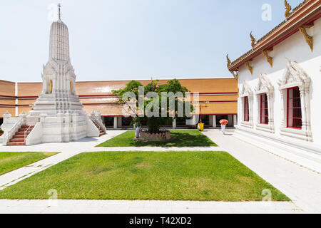 BANGKOK, THAÏLANDE - Mars 2019 : femme moine en robe blanche et orange marche parapluie dans la cour arrière de Golden Buddha temple complexe Banque D'Images