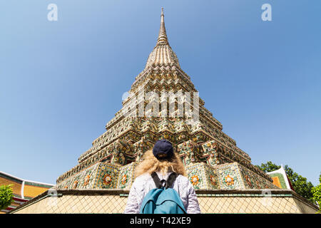 Sac à dos avec femme debout devant des stupa géant au bouddha couché de Wat Pho temple complexe à Bangkok, Thaïlande. Banque D'Images