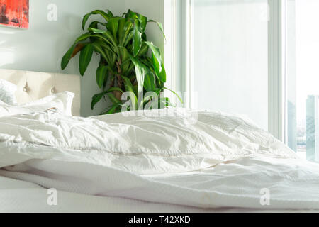Dormaient-en, vrai lit avec couette blanche dans une scène paisible sereine, représentant maison confortable, hôtel suite, rester dans son lit et de détente. Banque D'Images