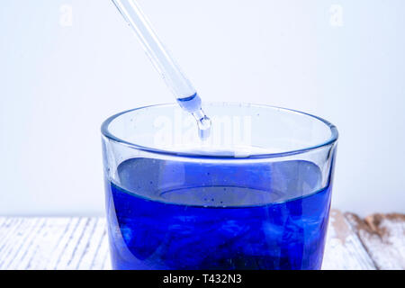 S'égoutte dans la pipette en verre avec un liquide bleu Banque D'Images