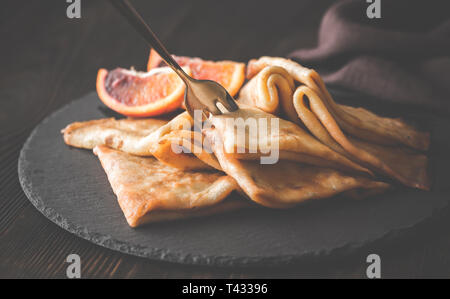 Crêpes Suzette avec des tranches d'orange sanguine sur le conseil de pierre noire Banque D'Images