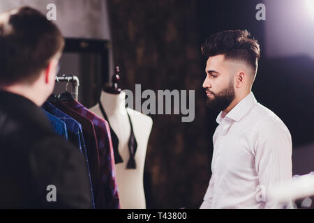 Client de sexe masculin au centre commercial d'essayer vêtements d'affaires, shop assistant aidant à client. Banque D'Images