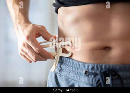Close-up d'une personne mesurant l'athlète son corps gras avec étrier dans la salle de sport Banque D'Images