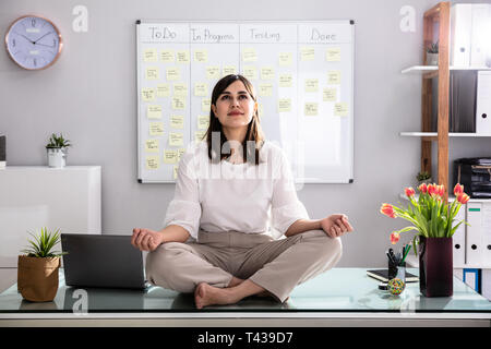 Young Businesswoman Sitting on Desk In Office Banque D'Images