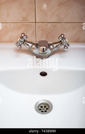 Vertical image de robinet fermé sur un évier de salle de bains blanc Banque D'Images