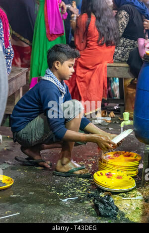 Vue verticale d'un jeune garçon lave-plaques dans les rues de Kolkata aka Calcutta, Inde. Banque D'Images