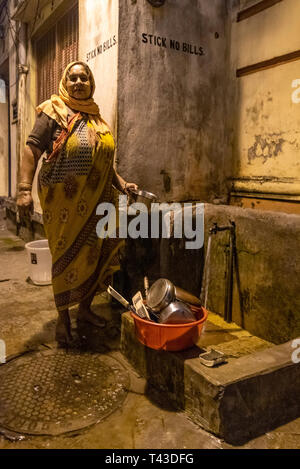 Portrait d'un vertical pauvre dame faisant sa lave jusqu'à une borne fontaine à Kolkata aka Calcutta, Inde. Banque D'Images