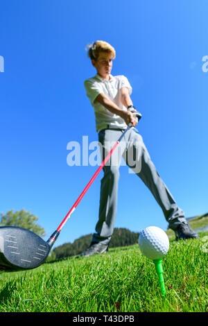 Jeune joueur de frapper une balle de golf avec chauffeur Banque D'Images