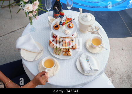 Une femme assise tenant un verre avec un haut plateau by a swimming pool Banque D'Images