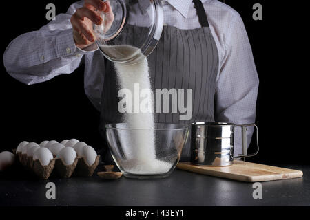 Verser dans un bol de sucre homme sur fond noir des tartes. concept. Banque D'Images