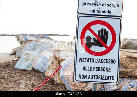 La lecture des panneaux d'avertissement : "Avertissement. Récif immergé de danger, des rochers sur le haut-fond sont présents' près d'un chantier de construction sur le littoral à Follonica, Italie Banque D'Images