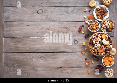 Mélanges de noix et fruits secs dans un bol en bois sur fond de bois, copie de l'espace. Collation santé - mélange de noix biologiques et des fruits secs. Banque D'Images