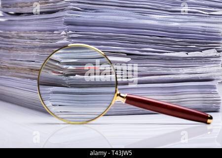 Close-up de loupe sur fond de la pile de dossiers papier. Banque D'Images