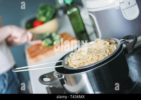 Spaghetti pâtes dans le moule sur le fond de la cuisine femme Banque D'Images