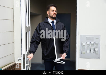 Technicien de jeunes hommes de l'ouverture de la porte tout en portant la main au bureau Banque D'Images
