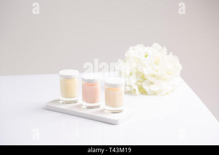 Trois pots de crème de soin naturelle bougie avec des fleurs d'été à fond clair Banque D'Images