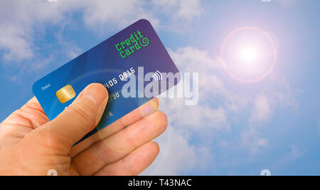 Hand holding credit card dans l'air contre un ciel bleu avec des reflets du soleil. Concept de voyage. Banque D'Images