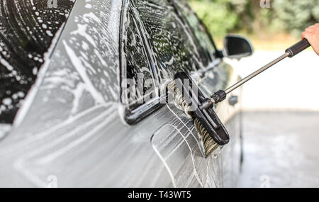 Côté de silver car lavés dans le libre service carwash. Détails sur les traits de pinceau laissant dans le shampooing mousse. Banque D'Images