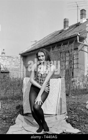 Jolie jeune femme slim debout dans jardin de maison traditionnelle hongroise 1960 Hongrie Banque D'Images