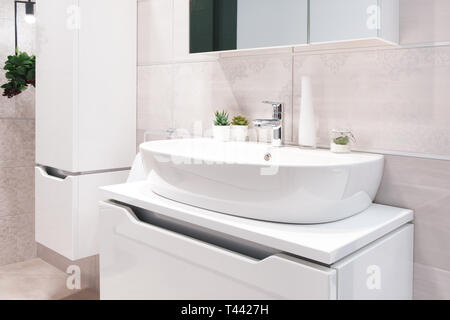 Mélangeur robinet de luxe sur une cuvette ronde lavabo blanc dans une belle salle de bains gris beige Banque D'Images