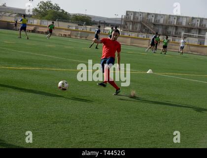 La marine française Maître de 2e classe Jonathan, amphibie heliporter, coups un ballon de soccer, au cours d'un match contre le personnel affecté à la Force opérationnelle combinée Force-Horn de l'Afrique (CJTF-HOA), au Camp Lemonnier, Djibouti, le 16 mars 2019. Plus de 50 marins français en compétition contre-HOA GFIM dans les deux membres de soccer amical et ultimate frisbee matches pour aider à favoriser une meilleure relation et l'esprit de corps entre les pays partenaires. Banque D'Images