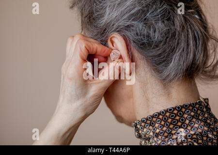 Libre senior woman insertion de prothèse dans ses oreilles. Banque D'Images