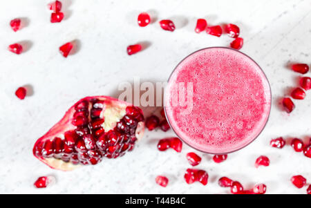 Smoothie Grenade avec gem floue comme les fruits éparpillés près de sur tableau blanc. À partir de la photo ci-dessus, l'accent sur des bulles dans la mousse de verre Banque D'Images