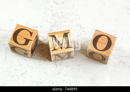Trois cubes en bois avec des lettres pour les OGM organisme génétiquement modifié sur un tableau blanc. Banque D'Images