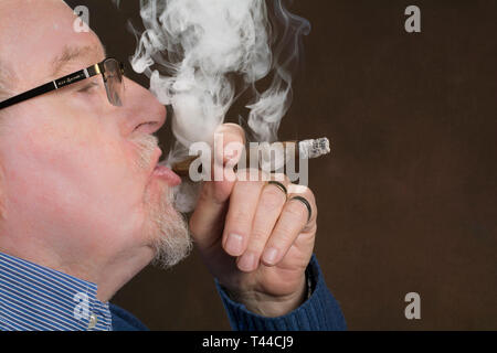 Un homme plus âgé bénéficiant d'un bon cigare fumeur Banque D'Images