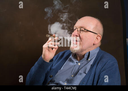 Un homme plus âgé bénéficiant d'un bon cigare fumeur Banque D'Images