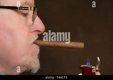 Un homme d'allumer un cigare avec un allume-cigare Banque D'Images