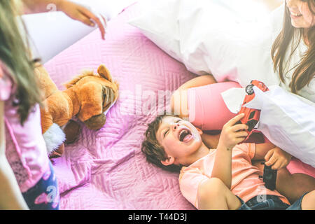 Happy Family les enfants jouant sur un lit avec des jouets et des oreillers - enfants ludique de s'amuser ensemble dans la chambre à coucher à la maison Banque D'Images