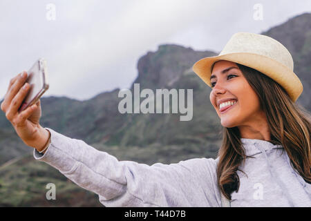 Belle jeune femme en prenant un congé avec son smartphone selfies mobile caméra avec vue sur la montagne dans l'arrière-plan Banque D'Images