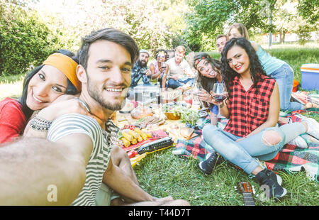 Groupe d'amis en prenant un dans le parc selfies lors d'une journée ensoleillée - Happy people faire un pique-nique de manger et boire du vin pendant la prise de photo Banque D'Images