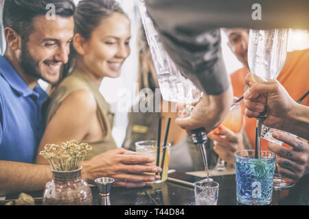 Heureux les jeunes amis s'amusant de prendre un verre au bar tout en barman préparer des cocktails et shot - deux couples à la recherche au barman Banque D'Images