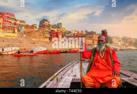 Sadhu baba assis sur un sol en bois surplombant l'ancienne ville de Varanasi architecture avec Gange ghat au coucher du soleil. Banque D'Images