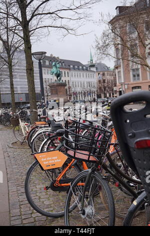 Prêt de vélos garés dans la rue avec la statue de ville fondateur derrière Absalon, Copenhague, Danemark Banque D'Images