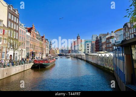 Amsterdam, Pays-Bas - Avril 2019 : marché aux fleurs flottant et bike park sur le canal Singel. Banque D'Images