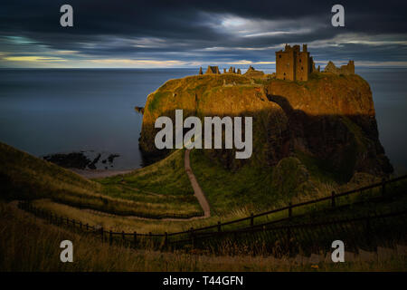 Dunnottar Castle sur de hautes falaises au coucher du soleil la lumière, côte est de l'Ecosse Banque D'Images