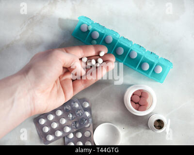 La main avec pills et casemate. Vue de dessus de sept jour comprimé fort avec des pilules. Comprimé vert-box plus de lumière table de marbre. Ouvrez la boîte de pilules et d'ouvrir les boîtes avec des pilules ou des vitamines. Copier l'espace. Vue d'en haut ou d''une télévision à jeter. Banque D'Images