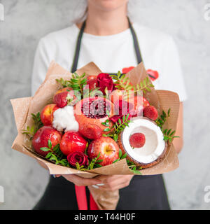 Bouquet de fruits et de baies. Bouquet de l'alimentation de femmes. Grenade, fraise, pommes, noix de coco et fleurs roses, d'eucalyptus. Shallow DOF Banque D'Images