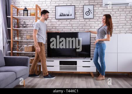 Vue latérale du jeune couple à la maison de la télévision de levage Banque D'Images