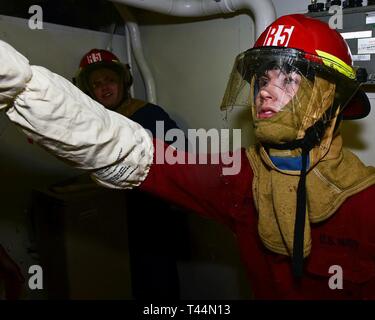 Mer de Chine orientale (fév. 21, 2019) - Machiniste 4400 Fireman Eric St-amand, de Biddeford, Maine, combat l'une simulation d'inondation blessé lors d'un exercice de la Brigade volante à bord de navire amiral de la flotte 7 USS Blue Ridge (CAC 19). Blue Ridge est le plus ancien navire opérationnel dans la marine et, en tant que navire de commandement 7e Flotte, travaille activement pour favoriser les relations avec les alliés et partenaires de l'Indo-Asia Région du Pacifique. Banque D'Images