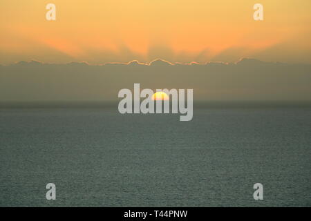 Le Golden sunset light ne traversent le ciel avec nuages sur l'océan Banque D'Images